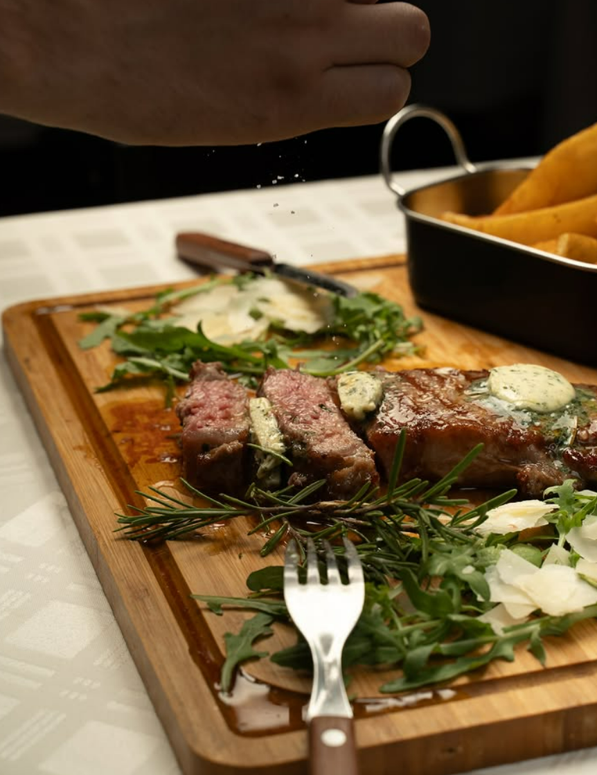 Aufgeschnittenes Steak mit Kräuterbutter auf Holzbrett